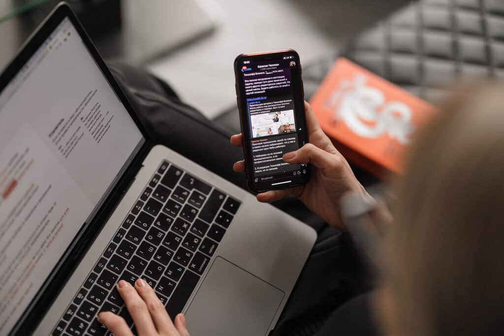person checking their phone and laptop